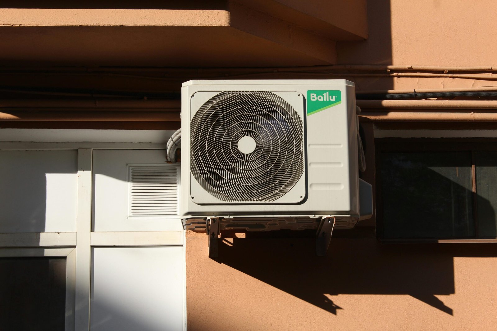A Ballu air conditioner condenser unit mounted on a building exterior, showcasing modern HVAC technology.